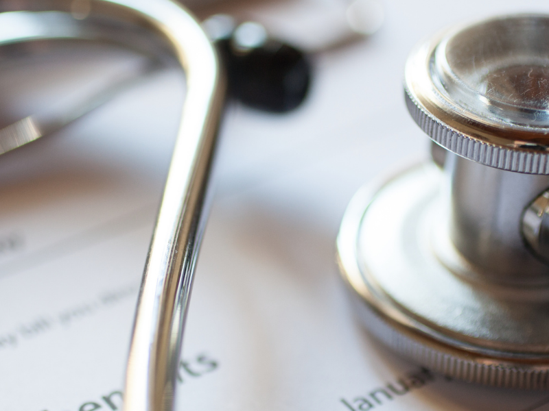 Close-up of a stethoscope resting on a medical form or bill, suggesting healthcare administration.
