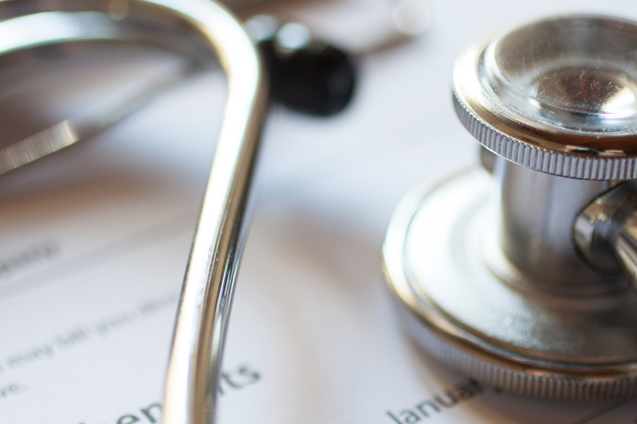 Close-up of a stethoscope resting on a medical form or bill, suggesting healthcare administration.
