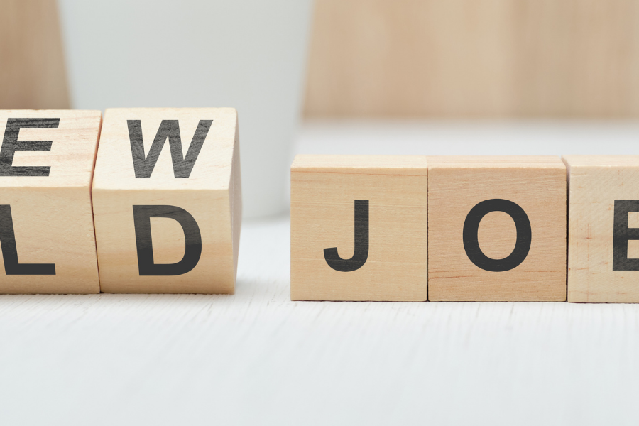 Wooden letter blocks spell ‘NEW OLD JOB’ on a light surface, suggesting a career change.