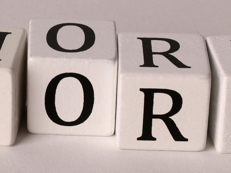 Blocks spelling 'MORE' arranged in a row on a light surface.