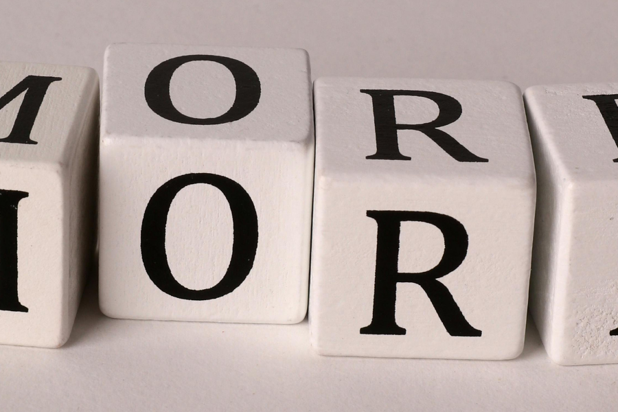 Blocks spelling 'MORE' arranged in a row on a light surface.