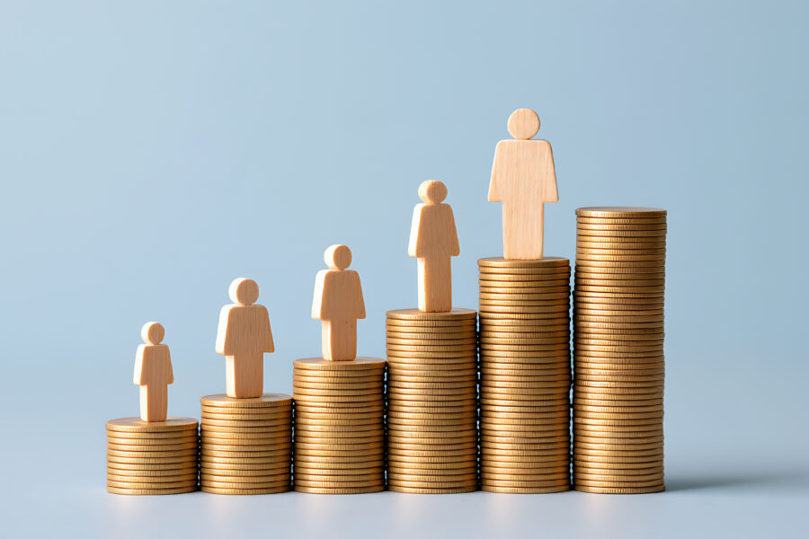 Wooden figures of increasing size standing on rising stacks of coins