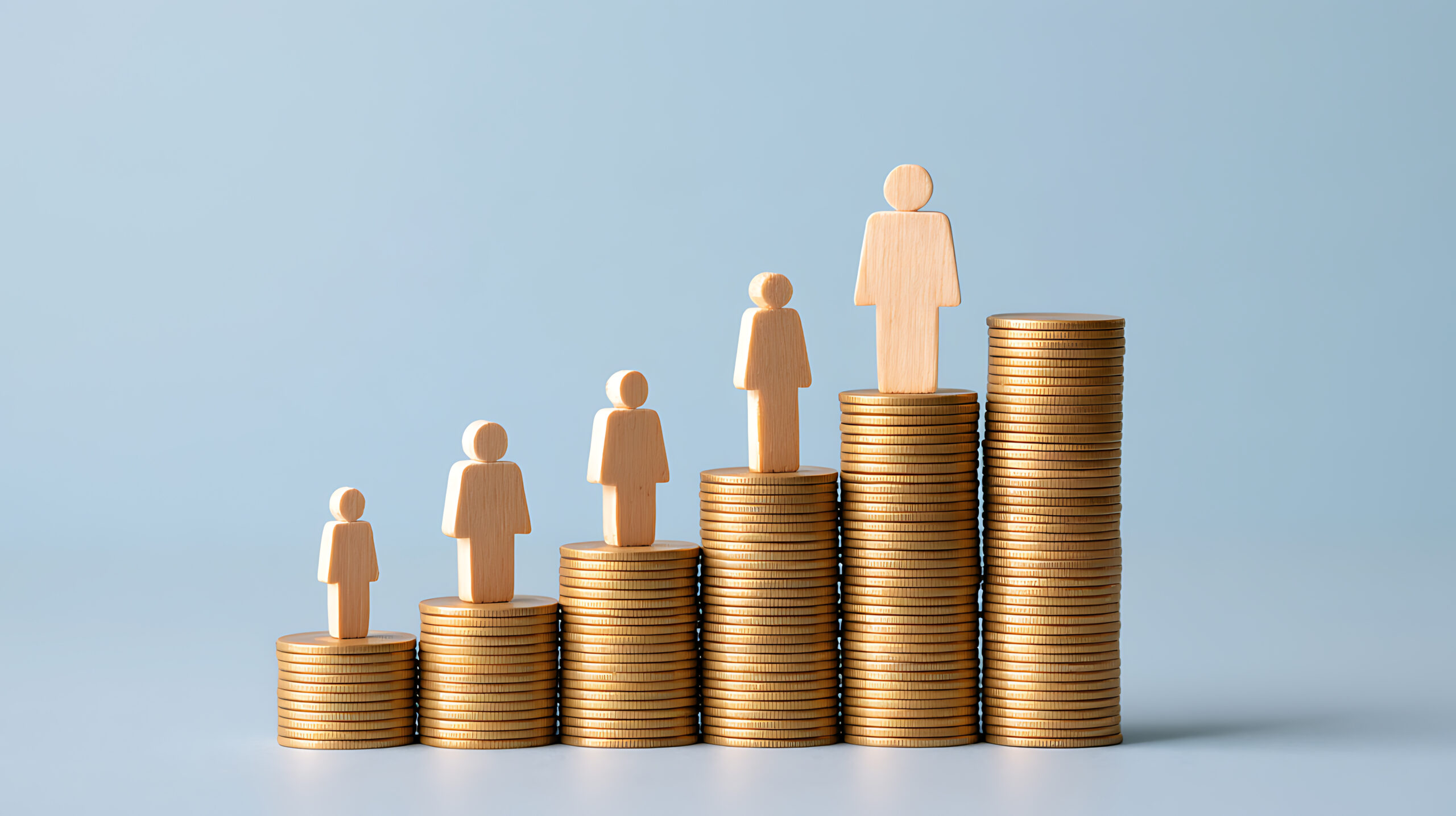Wooden figures of increasing size standing on rising stacks of coins